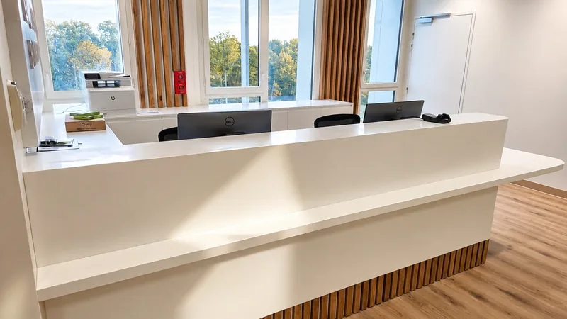 L'accueil du cabinet, son comptoir blanc devant les grandes fenêtres