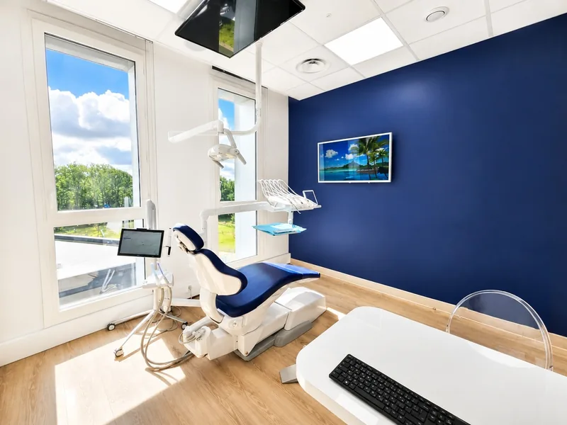 Une salle de soins du cabinet, mur bleu marine et grandes fenêtres
